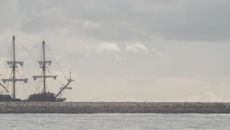 16th-Century-Galleon-Andalucia-replica-ship-arriving-at-port-in-a-beautiful-cloudy-day-at-sunrise-behind-a-breakwater