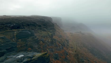 Aerial:-Beautiful-steep-cliffs-shrouded-in-thick-slow-moving-mist