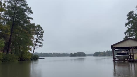Rainy-Lake-in-East-Texas-fall-leaves-fishing-rain-drops-hitting-green-water-with-fishing-dock-nearby