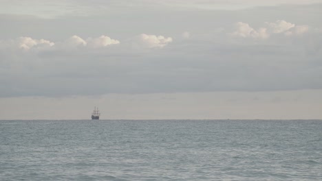 16th-Century-Galleon-Andalucia-replica-ship-sailing-in-the-distance-in-the-calm-Mediterranean-sea-in-a-cloudy-day-at-sunrise