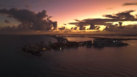 Aerial-view-away-from-the-Punta-Cancun-bay,-cloudy-sunset-in-Mexico---pull-back,-drone-shot