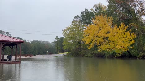 Rain-falling-on-Texas-Lake-in-the-fall-with-yellow-and-orange-leaves-on-the-trees-near-fishing-boat-and-dock-in-East-Texas