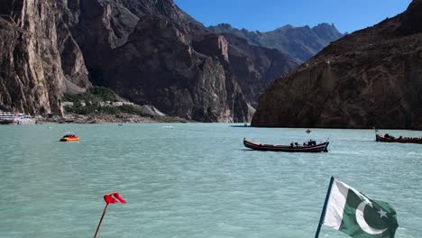 Luftaufnahme-Des-Attabad-Sees-Mit-Pakistanischer-Flagge-Auf-Dem-Boot-Und-Bergkette-Im-Blick