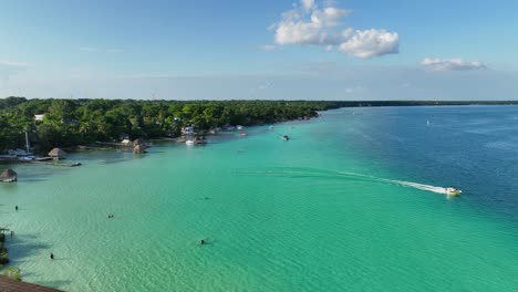 Aerial-view-boat-leaving-the-Bacalar-town,-in-sunny-Mexico---static,-drone-shot