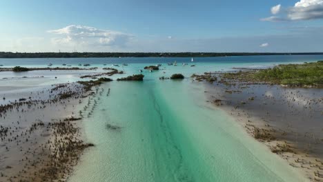 Aerial-view-over-the-lagoon-and-the-Canal-de-los-Piratas-towards-the-Bacalar-town,-in-sunny-Mexico---rising,-drone-shot