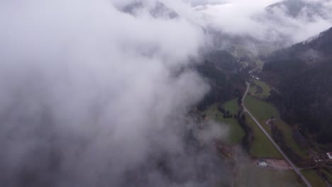 Vista-Aérea-De-Un-Camino-De-Pueblo-De-Montaña-Debajo-De-Las-Nubes-Durante-El-Otoño-En-Vosges,-Francia,-4k