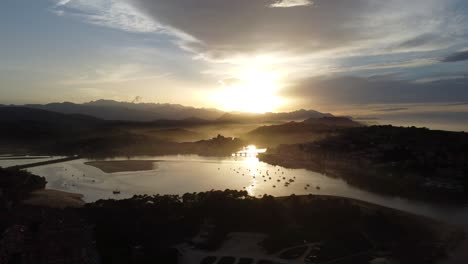 Die-Erstaunliche-Stadt-San-Vicente-De-La-Barquera-In-Kantabrien-In-Nordspanien-Vor-Einem-Atemberaubenden-Sonnenuntergang-Mit-Nebel-Und-Wolken,-Drohne