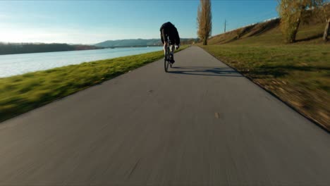 Hectic-FPV-shot-of-racing-Jake-the-Fixedgear-Biker-next-to-Danube-river-during-sunny-late-autumn-day