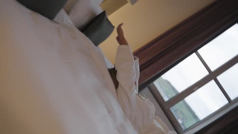 Women-with-blond-hair-in-a-white-bathrobe-in-a-hotel-room-falling-backwards-down-on-the-bed-at-the-evening