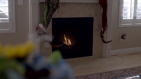 Warmer-Und-Gemütlicher-Kamin-Im-Hintergrund-Mit-Defokussierten-Blumen-Im-Vordergrund-Und-Hängenden-Weihnachtsstrümpfen---Parallax-Bewegungsszene
