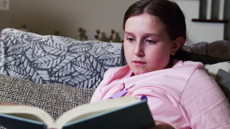 Young-girl-reading-book-in-living-room