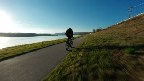 Tiro-Rápido-Fpv-Del-Ciclista-De-Carreras-Jake-El-Ciclista-De-Equipo-Fijo-Junto-Al-Río-Danubio-En-El-Colorido-Día-De-Otoño
