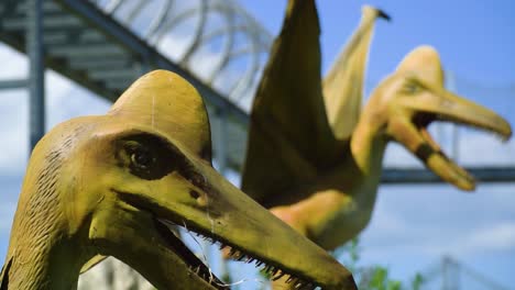 two-pterodactyl-ancient-historic-beasts-realistic-looking-models-with-open-mouths-protecting-their-territory-one-of-them-moving-his-head-from-left-to-right-mechanical-creatures-brown-wooden-sunny