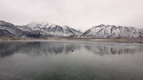 Extreme-wide-shot-of-a-lonely-person-digging-ice-for-fishing-on-frozen-Crowley-Lake