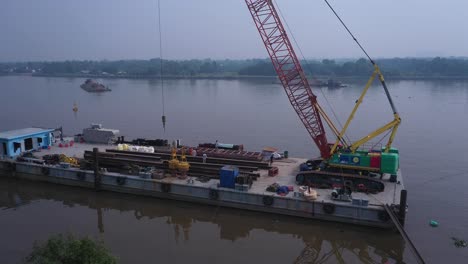 Aerial-fly-in-to-dredging-equipment-and-workers-on-a-barge-on-the-Saigon-River-in-Ho-Chi-Minh-City,-Vietnam