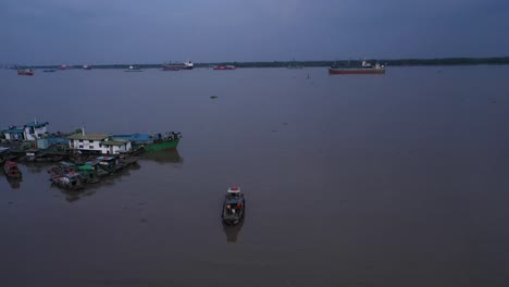 Top-down-Aerial-tracking-view-of-working-boats-and-jetty-on-Saigon-River-waterfront-in-late-afternoon-light