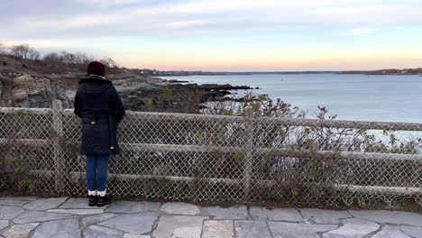 Rückansicht-Einer-Einsamen-Frau,-Die-Am-Zaun-Am-Aussichtspunkt-Am-Golf-Von-Maine,-USA,-Steht