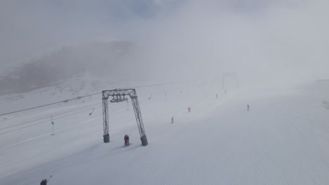 Esquiador-De-Sobrevuelo-Aéreo-Esquiando-Pendiente-Nevada-Durante-El-Día-Brumoso-Al-Lado-Del-Remonte-En-Austria