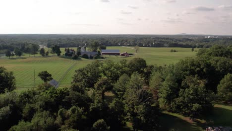 Aerial-footage-of-a-quaint,-traditional-looking-farm-with-a-lone-mountain-in-the-distance