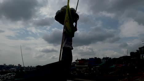 Täglicher-Arbeiter,-Der-Einen-Korb-Mit-Gemüse-Im-Kopf-Am-Flusshafen-In-Bangladesch-Trägt