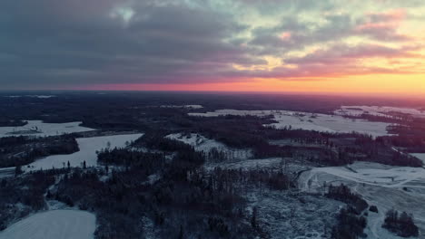 Drohne-Fliegt-über-Verschneite-Landschaft-Mit-Sonnenuntergang-Im-Hintergrund