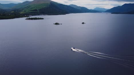 Luftdrohnenaufnahme-Eines-Weißen-Schnellboots,-Das-An-Einem-Bewölkten-Tag-über-Loch-Lomond-Segelt