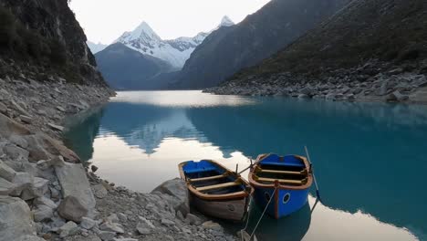 boat-moored-in-Lake-Paron,-Pyramid-Mountain-reflection-on-still-water-Andean-Cordillera-in-Peru-Huascaran-National-Park