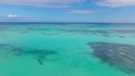 Aerial-over-idyllic-shallows-and-reefs-of-Caribbean-ocean,-boat-cruise-past