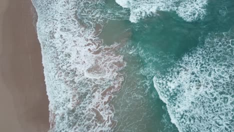 Aerial-top-down-view-over-clear,-Turquoise-ocean-water-boiling-and-foaming-at-shore,-washing-the-golden-sand-of-the-beach-Idyllic-summer-vacation-on-Hawaii-island