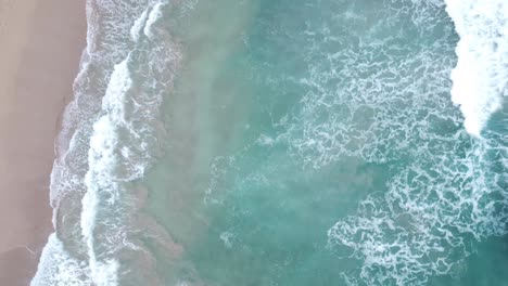 Aerial-top-view-over-clear,-Turquoise-ocean-water-foaming-at-the-shore,-washing-the-golden-sand-of-the-beach,-Idyllic-summer-vacation-on-Hawaii-island