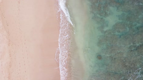Aerial-top-down-view-over-clear,-Turquoise-ocean-water-boiling-and-foaming-at-the-shore,-washing-the-golden-sand-of-the-beach-Idyllic-summer-vacation-on-Hawaii-island