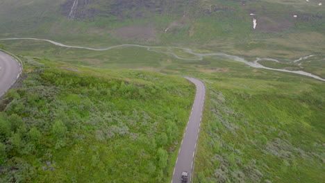 Jeep-driving-down-winding-mountain-road-on-rainy-day-in-Scandinavia