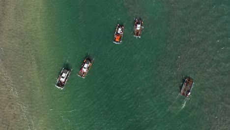 Aerial-birdseye-view-of-a-group-of-small-ferry-boats-carrying-cars-crossing-a-large-shallow-river-with-wind-causing-small-waves-on-the-surface,-Northern-Brazil