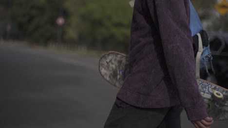 HD30-SLOW-MOTION-Close-up-skater-walking-by-the-street-with-skateboard
