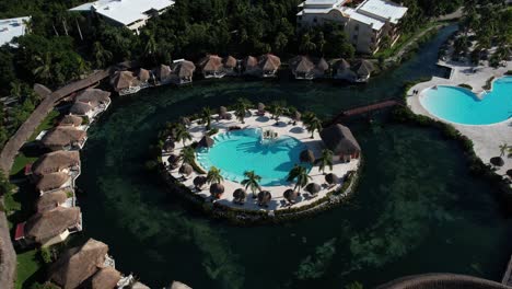 Aerial-View-of-Luxury-Bungalows-in-a-Tropical-Lagoon-With-Central-Swimming-Pool