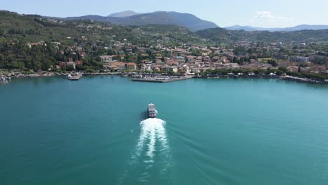 Aerial-shot-following-large-cruise-ship-entering-Garda-Harbor,-Lake-Garda,-Italy