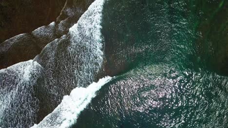Overhead-drone-shot-of-beach-waves-with-clear-water-and-visible-the-coral-rocks