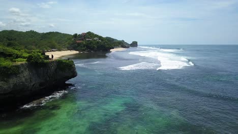 Aerial-forward-shot-of-beautiful-coastline-with-waves-and-sandy-beach-during-sunny-day-in-Indonesia,-Java