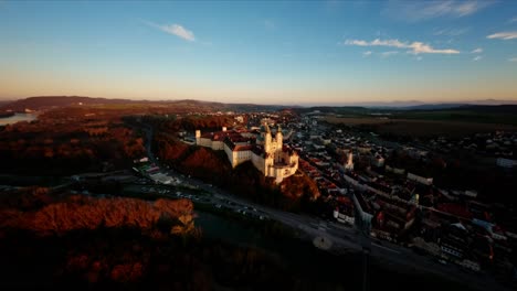 Smooth-FPV-orbit-shot-of-painterly-castle-Melk-during-warm-late-autumn-sunset
