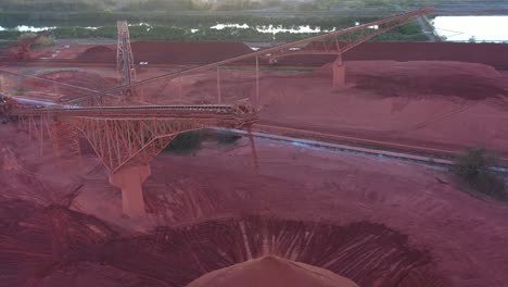 Drone-orbiting-shot-of-Red-Coal-dropping-from-mining-conveyor-belt