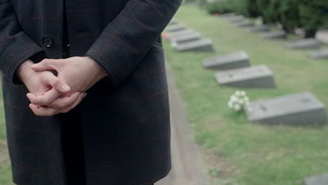 Formally-dressed-man-is-standing-at-the-grave-of-a-loved-one,-grieving-and-sadness-concept