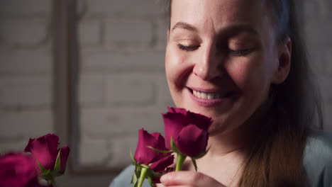 An-attractive-woman-smells-a-bouquet-of-red-roses-and-a-smile-appears-on-her-face