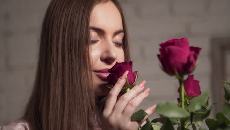 Young-attractive-woman-smelling-a-bouquet-of-roses