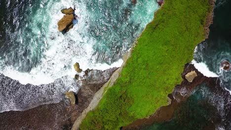 Overhead-view-of-tropical-ocean,-breaking-waves-and-green-forest-in-Indonesia