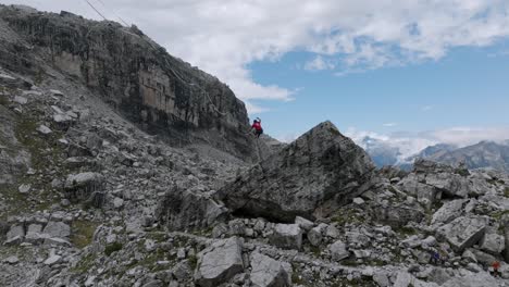 Persona-Saltando-En-Slackline-En-Las-Montañas-Dolomitas-De-Brenta-En-Verano,-Tiro-De-Seguimiento-De-Drones