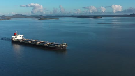 Drone-panning-shot-of-Large-Coal-Ship-Leaving-Port,-Gladstone-Queensland-Australia