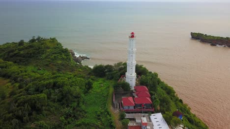 Towering-white-lighthouse-aerial-view-above-Baron-Beach-on-Java-Island-Indonesia