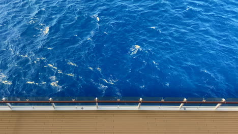 View-of-blue-ocean-while-looking-down-from-top-deck-of-sailing-cruise-ship