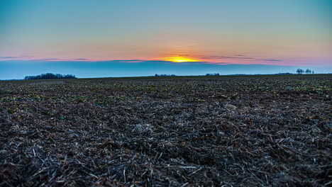 Sunrise-time-lapse-over-a-harvested-field-of-farmland-crops