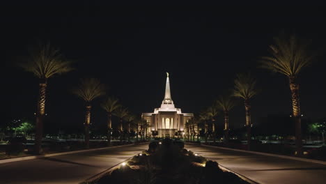 LDS-Church-Mormon-Temple-at-Night-in-Gilbert,-Arizona-from-a-Distance-with-Road-Lined-with-Palm-Trees-leading-to-the-LDS-Temple